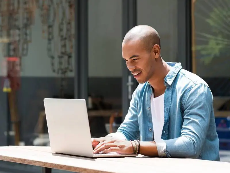 A man sitting at a table with a laptop.