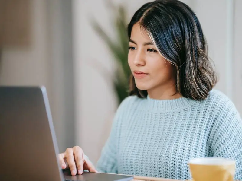 A woman sitting at a table using her laptop.