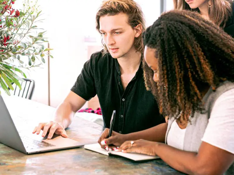 A man and woman working on laptops at a table.